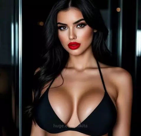 Woman with dark hair and makeup wearing a black bikini top drinks beer from a large glass.