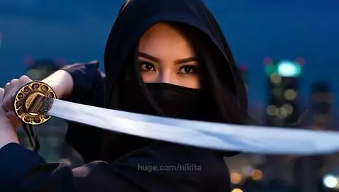 Woman in black hooded outfit with a katana on a city rooftop at night, city skyline in background.