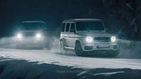 Two Mercedes-Benz G-Wagons drifting on a snowy mountain road at night, kicking up snow.