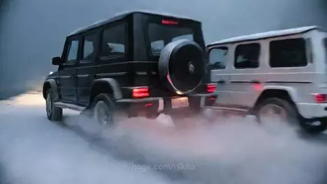 Two Mercedes G-Wagens driving on a narrow, rickety bridge over a chasm in a snowy mountain landscape.