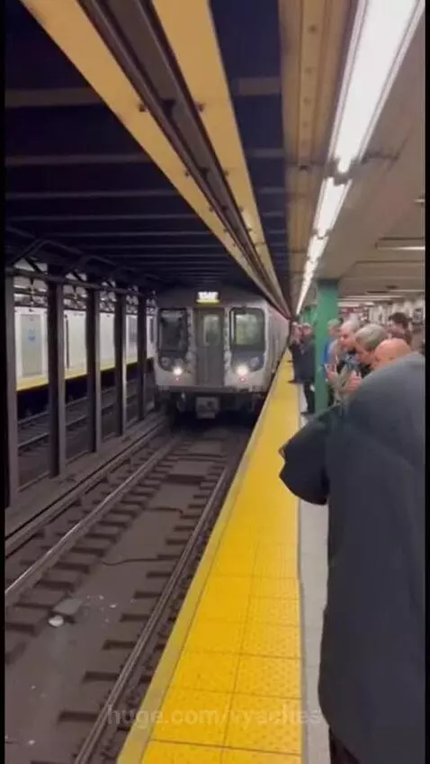 Person in swimsuit and swimming cap pushes a man onto subway tracks as a train approaches.