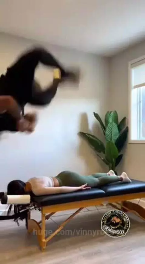 Chiropractor's table broken in half after a failed backflip attempt, woman on table looks surprised.
