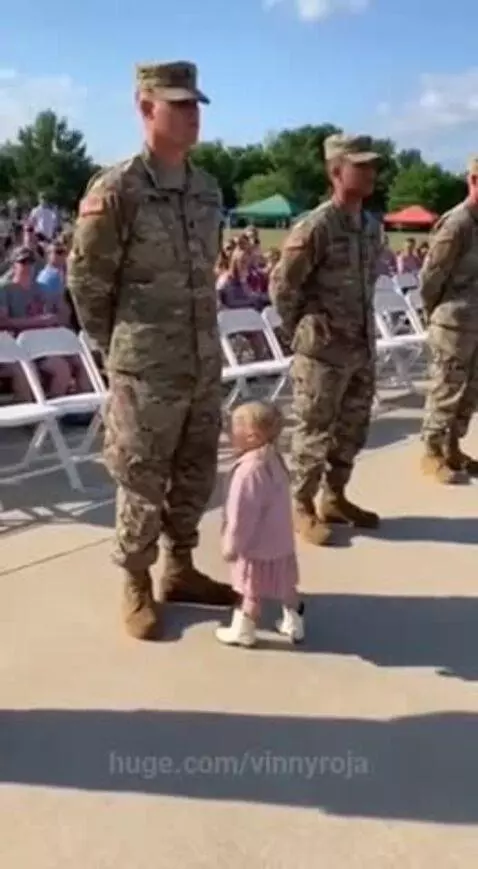Young child in pink dress points at a soldier and delivers a message about ice cream.