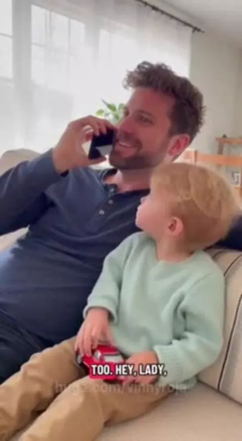 Man with beard on couch smiling, child next to him holding toy car.