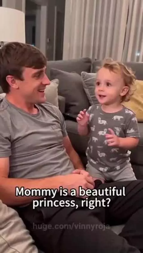 A man laughs as a child sits on his lap and asks a funny question about eating a prince.