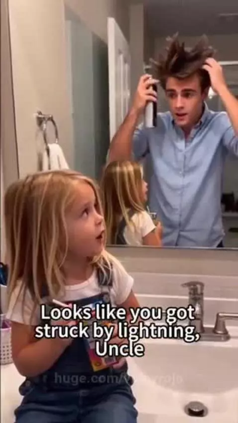 Man with spiky hair looking in mirror, girl on counter holding juice box.