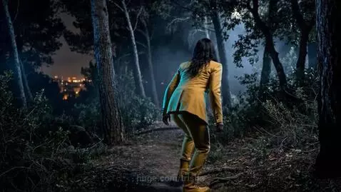 Two women looking at a metallic UFO in a dark forest at night.