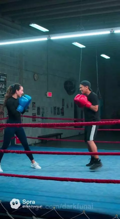 Man and woman playfully sparring in boxing gloves, woman lands a punch on the man.