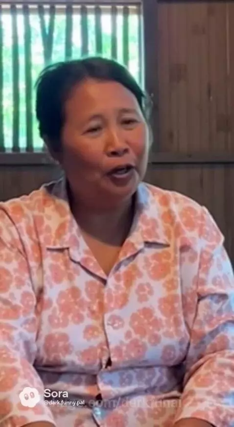 Family sharing a large platter of food on the floor in a rustic room, laughing and talking.