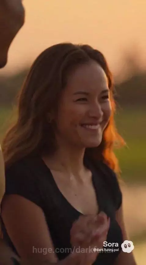 Couple walking hand-in-hand on a dirt path beside a flooded rice paddy field at sunset.