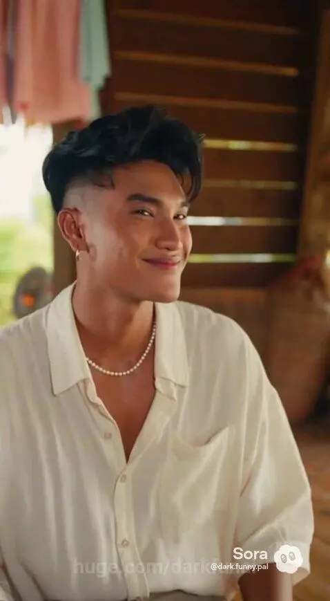 Older woman playfully scolds younger man sitting on a mat inside a rustic wooden house.
