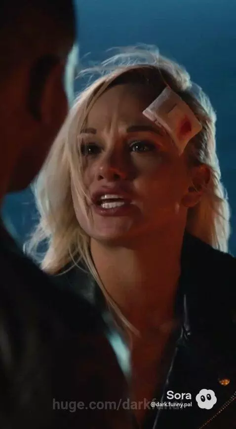 Close-up of a distressed blonde woman with a forehead bandage, wearing a leather jacket, speaking emotionally.
