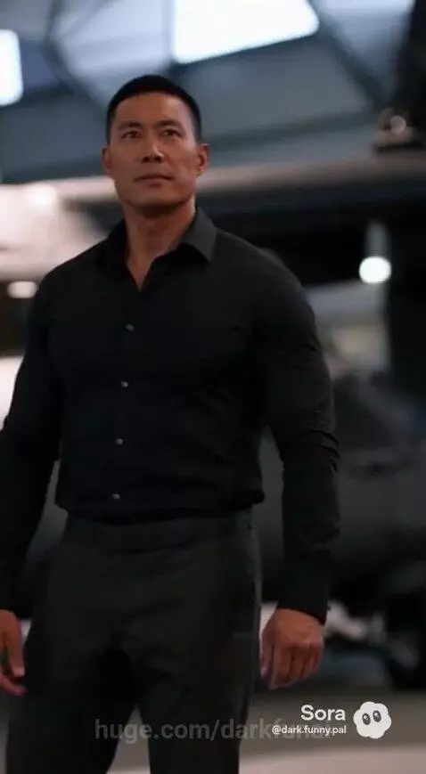 Soldier in a hangar with a helicopter, discussing new military technology.