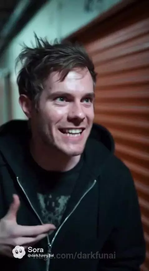 Two men in a lab with a large, glowing purple and pink circular device surrounded by wires and servers.