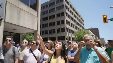 Crowd looking up at a building with a sign reading 'Rapid Emergency Tactical Alien Response Division Retard'.