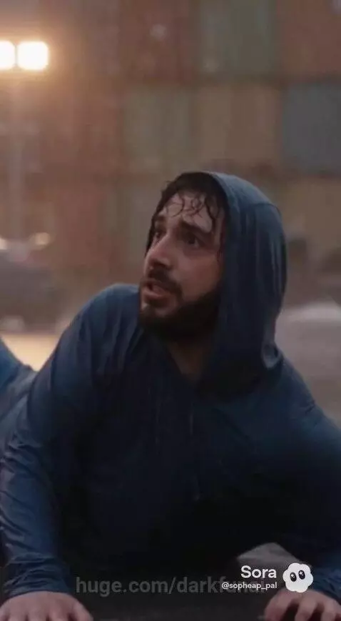 Superhero in a blue suit with glowing eyes fighting a large, armored robot with red eyes in the rain.