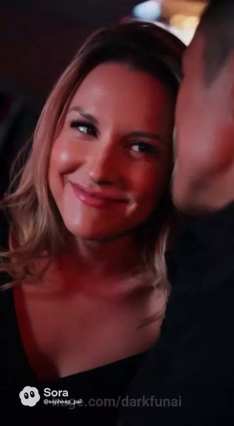 Couple in car at night, city lights, man teases woman about her serious face, they hold hands.