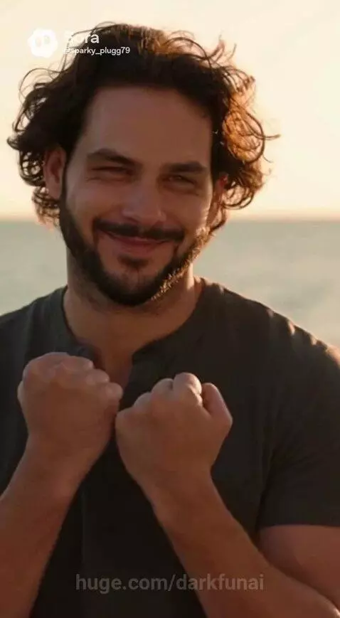 A man and woman in glowing superhero suits fight on a pier at sunset.