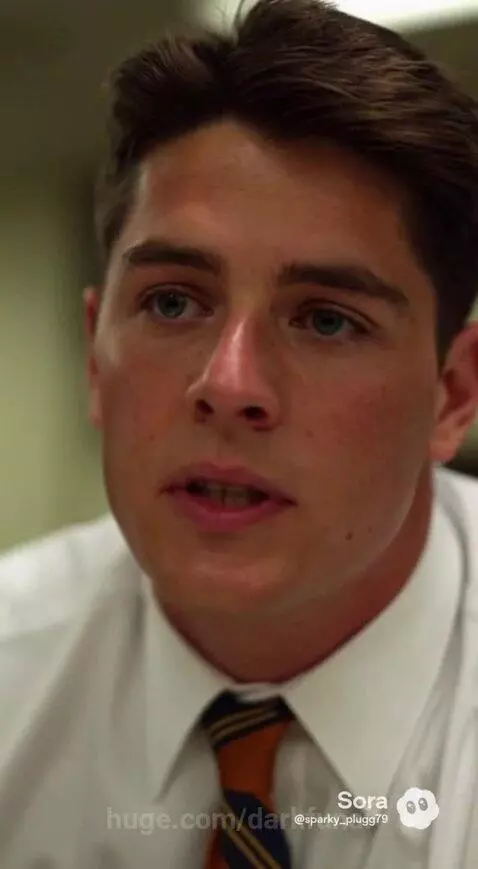 Man in suit with glasses reviews legal documents at desk, discussing child custody with a woman and another man.
