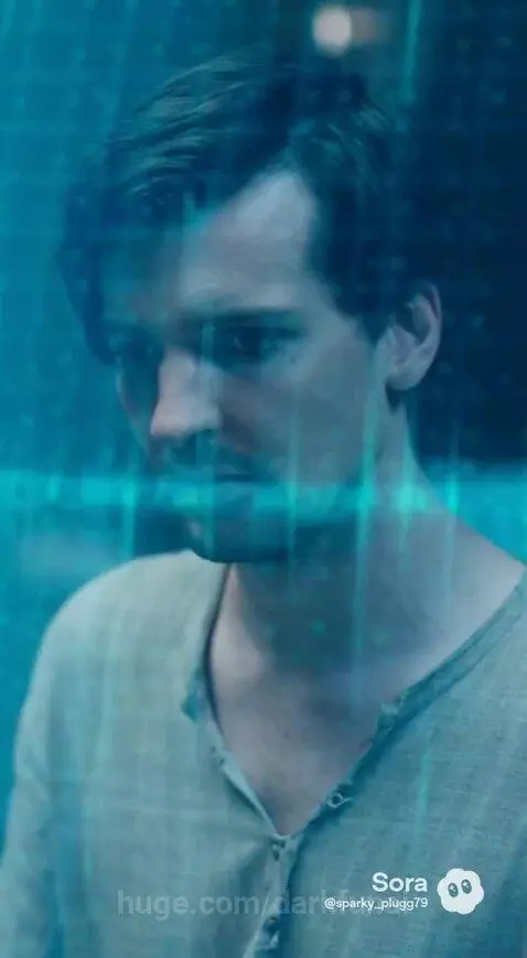 Man in meditative pose in a blue containment field, woman in green dress questions his return.