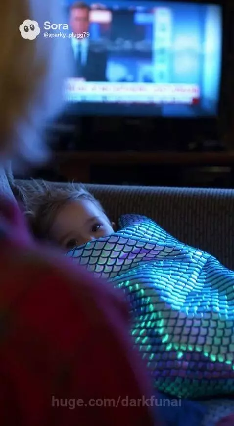 Young woman and child watch a news report about a meteor strike; older woman looks concerned.