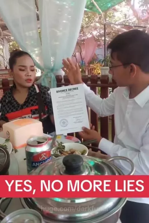 Man smiling and raising arms in celebration at an outdoor table after receiving a divorce decree.
