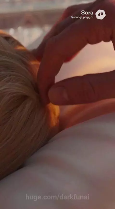 A man in a white robe touches Marina's hair in a glowing coffin as guards prepare to load it into a futuristic spacecraft.