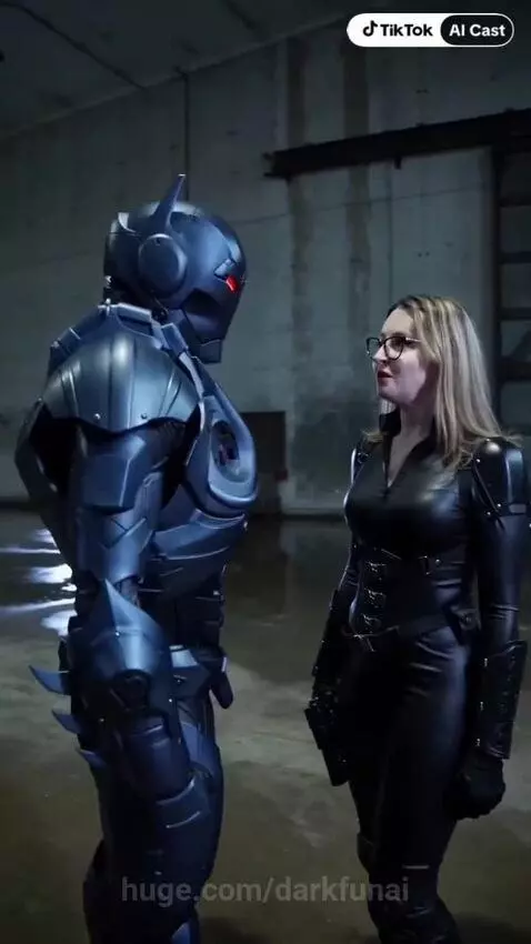 Woman in black futuristic suit flirts with a man in red-eyed robotic armor, reflection in visor.