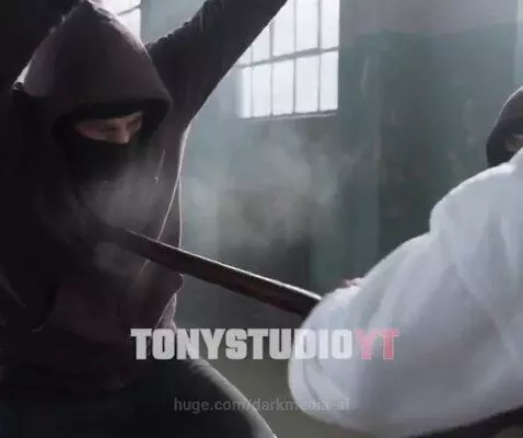 Martial artist in white gi and black belt fighting multiple attackers with a bo staff in a warehouse.
