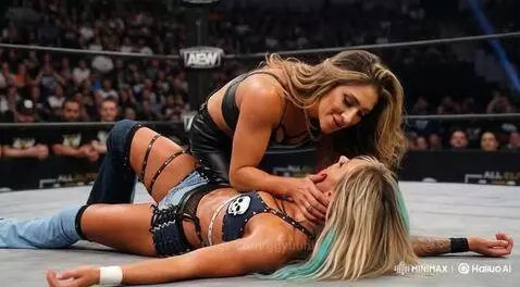 Wrestler Sol Ruca kisses another wrestler lying on the mat in a wrestling ring.