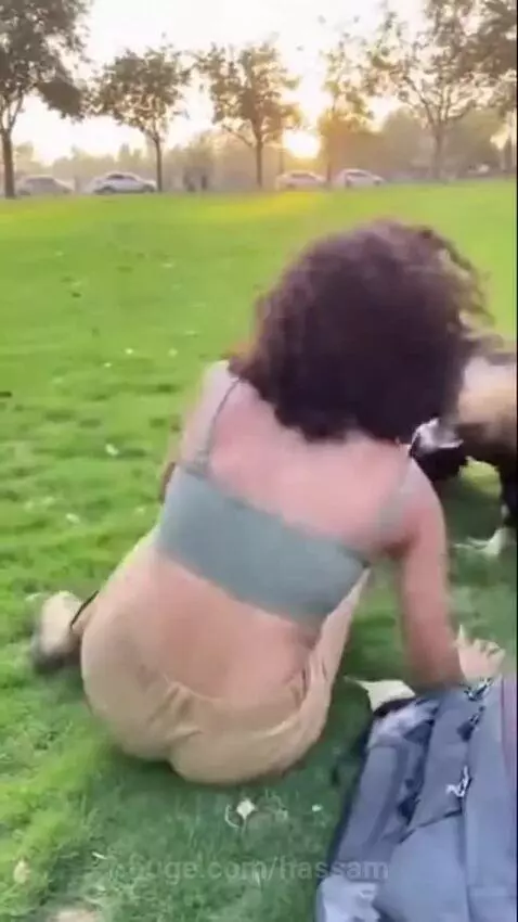 Woman on grassy field being attacked by an eagle pulling at her green top.