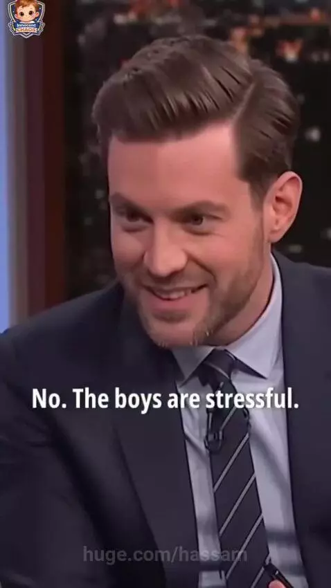 Young girl in overalls on a talk show couch, confidently telling an interviewer that boys are stressful.