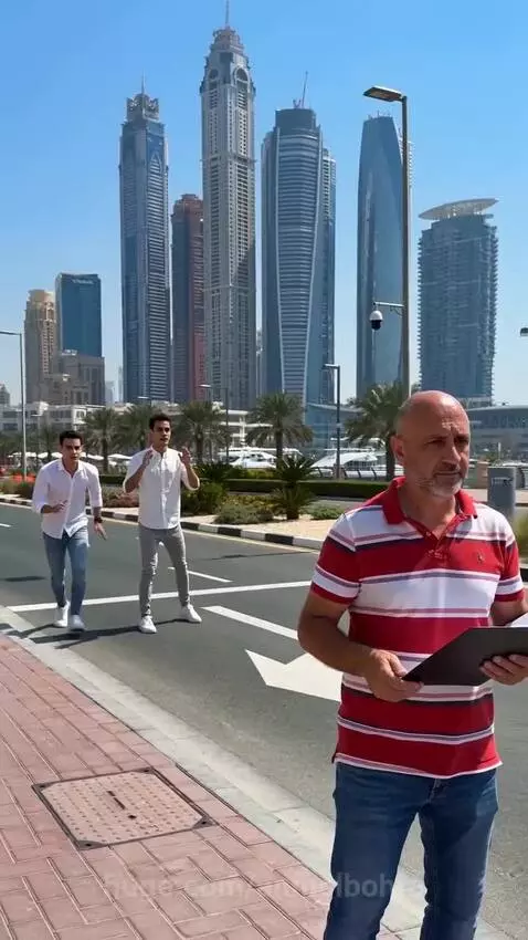 Two men playfully prank an older man on a sunny city street, snatching his folder.