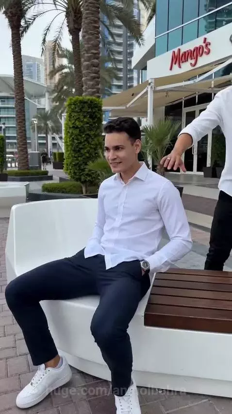 Three young men in an urban setting with palm trees, one man pushing another off a bench as part of a prank.