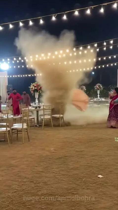 Dust devil swirling at an outdoor wedding reception, overturning chairs and surprising guests.