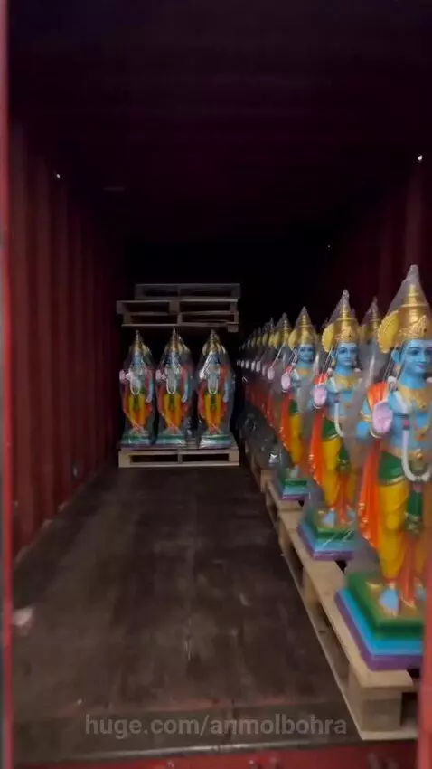 Hundreds of colorful Hindu deity statues neatly arranged on pallets inside an open shipping container on a boat.
