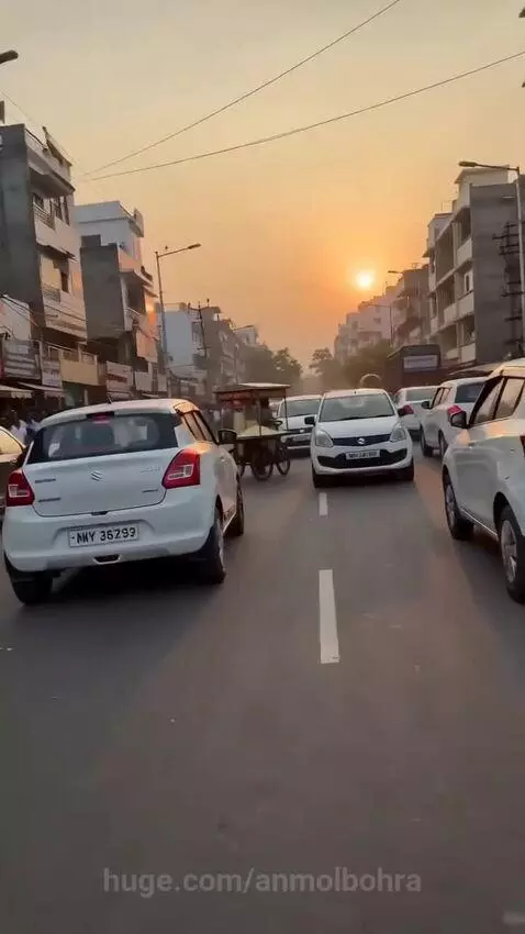 A cow jumping onto the hood of a white car, smashing the windshield, with popcorn scattered on the street at sunset.
