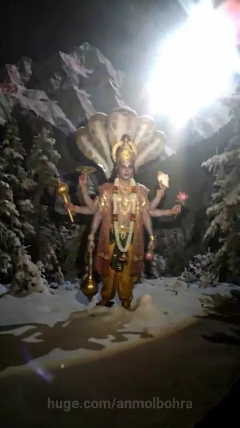 Intricate multi-armed Hindu deity statue in a snowy mountain landscape with a halo effect.