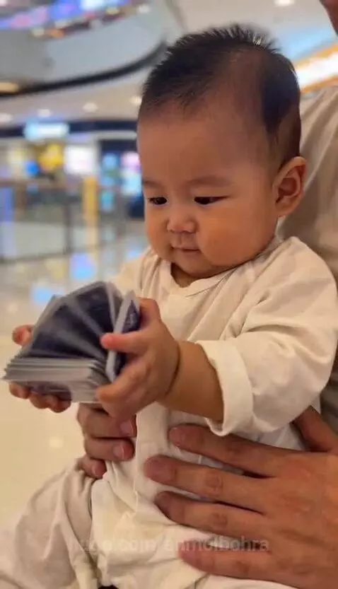 Baby watching a card trick with intense focus, then smiling and laughing joyfully.