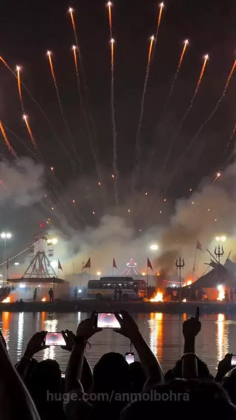 Fireworks display forming the image of Goddess Kali with multiple arms and glowing red eyes over a body of water.