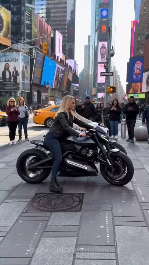 Four women posing confidently on various motorcycles in a bustling Times Square, NYC, with digital billboards and taxis in the background.
