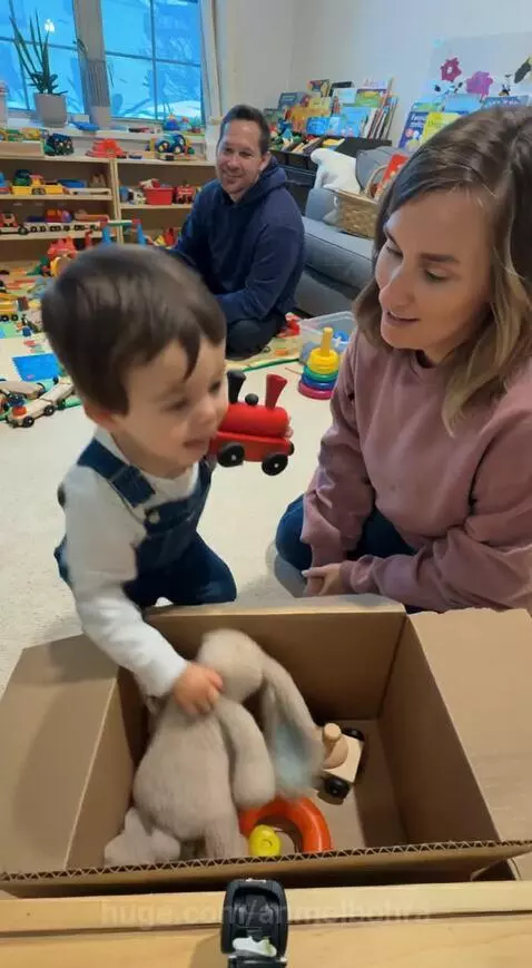 Toddler boy in overalls protests as mom puts toys in a box, claiming 'Mine too!'