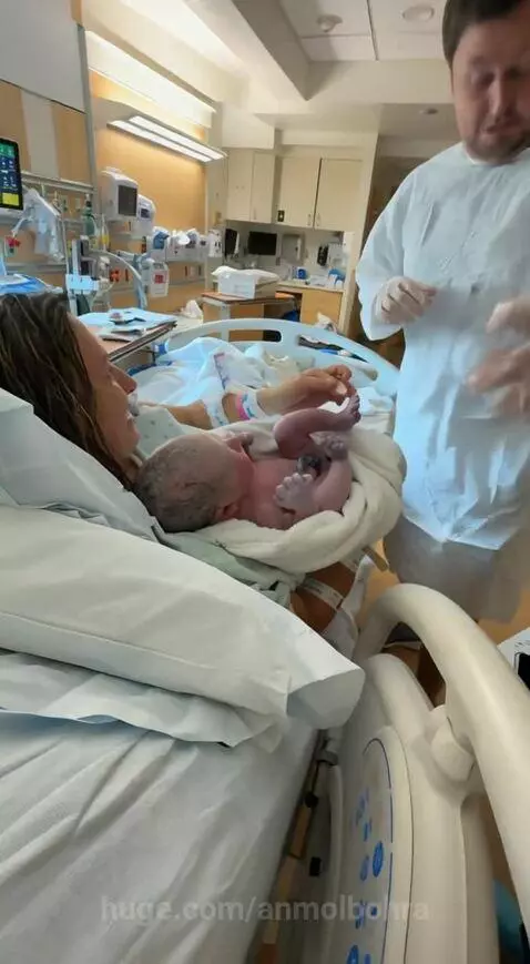 Newborn baby's foot making an ink print on a father's white hospital gown.