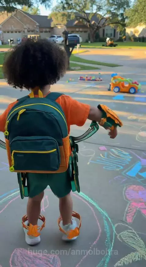 Toddler in orange shirt and green shorts, backpack transforms into a futuristic green and gold flying suit with helmet.
