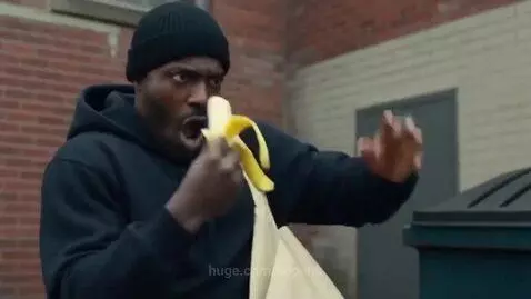 Man in black hoodie eating a banana, suddenly has large muscular arms glowing with a golden aura.