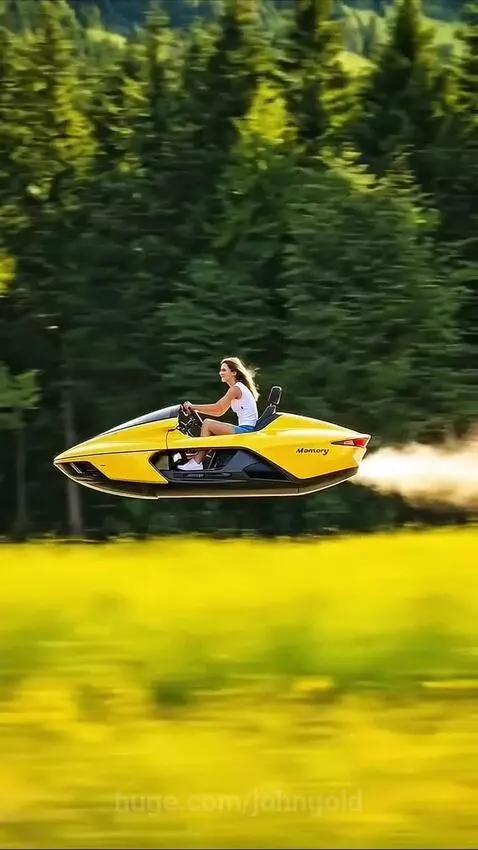 Woman driving a bright yellow Mansory futuristic hovercraft over a green field with a forest in the background.