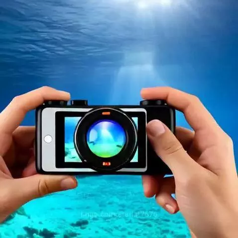 Underwater scene with clear blue water, sandy seabed, coral, and a manta ray swimming past a camera.