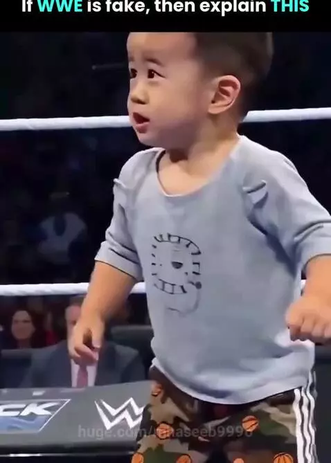 Dwayne 'The Rock' Johnson gently catches a baby in a wrestling ring as the crowd cheers.