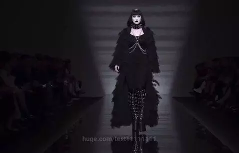 Goth model on a dark runway with a dramatically expanded, obese belly, illuminated by spotlights.