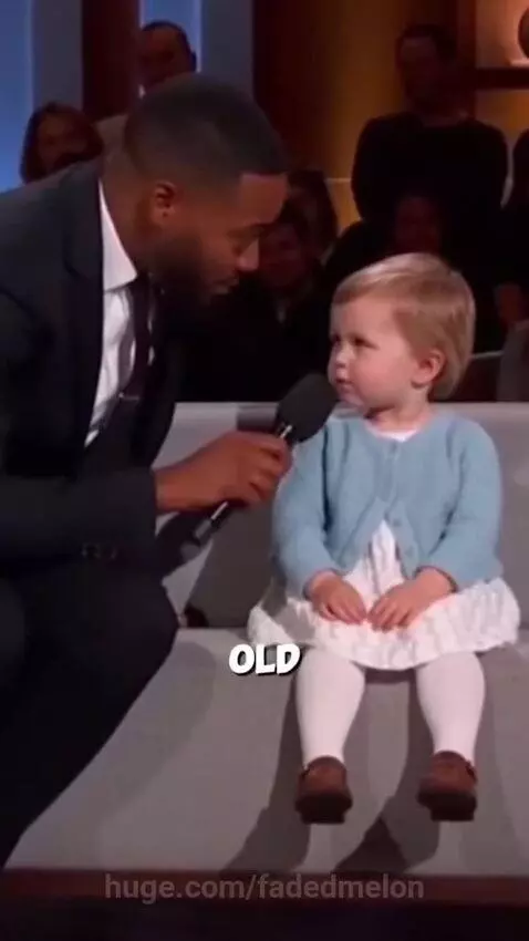 Young girl with blonde hair smiles as a man laughs holding a microphone, after she called a 40-year-old man 'expired'.